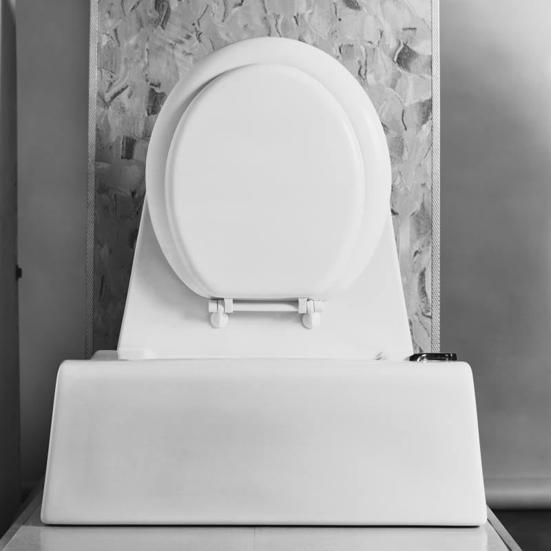 A close-up view of a white toilet with the lid closed, set against a textured wall—often found near a commercial lift station for efficient wastewater management.
